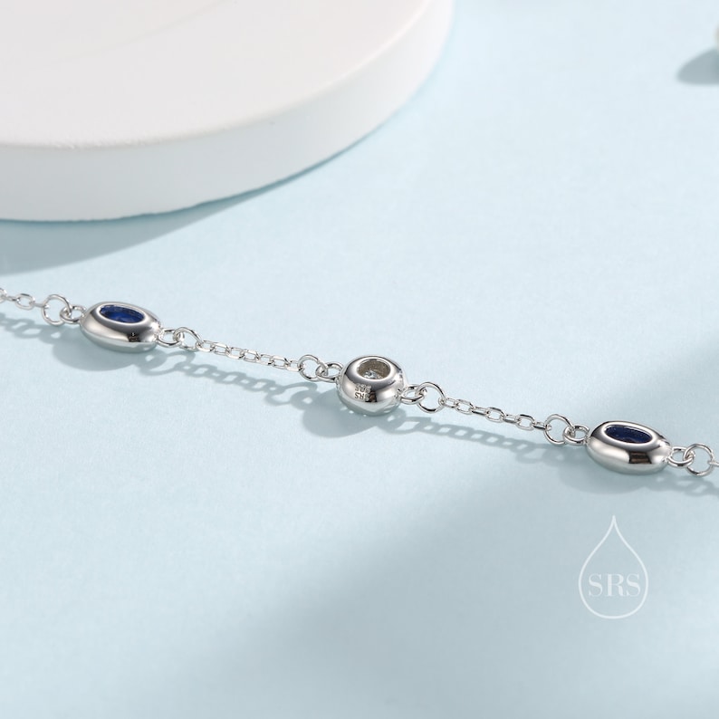 Peut inclure: Un bracelet en cha&icirc;ne argent avec trois pierres bleues de forme ovale et une seule pierre ronde au centre.