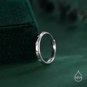 May include: A silver ring with small, clear stones set in the shape of stars around the band.