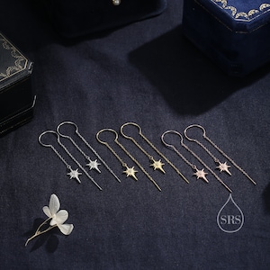 May include: Six pairs of dangle earrings with a starburst design featuring a single clear stone in the center. The earrings are available in silver, gold, and rose gold.