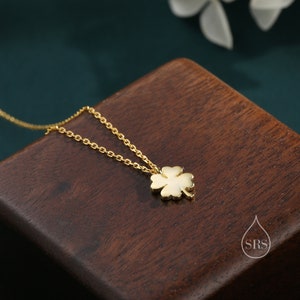 May include: A gold chain necklace with a four-leaf clover pendant. The pendant is made of gold and has a white enamel finish.