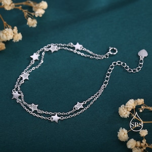 May include: A delicate silver bracelet with a double chain design featuring small star charms adorned with tiny clear crystals.