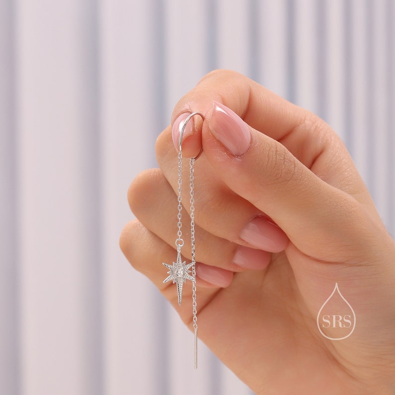 May include: Silver chain earrings with a star-shaped charm featuring a clear crystal in the center.