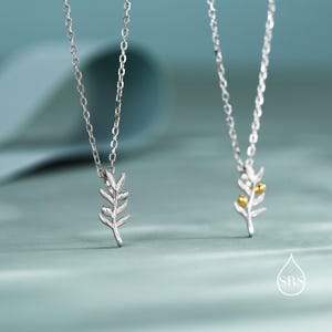 May include: Two silver necklaces with olive branch pendants. One pendant has gold-coloured olives, the other has silver olives.