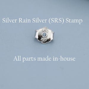 May include: A close-up of a silver earring back with the text "Silver Rain Silver (SRS) Stamp" and "All parts made in-house" on a light blue background. The earring back has a floral design.