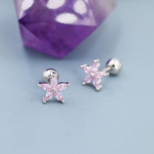 May include: A pair of silver flower-shaped earrings with pink cubic zirconia stones. The earrings are designed for cartilage piercings.