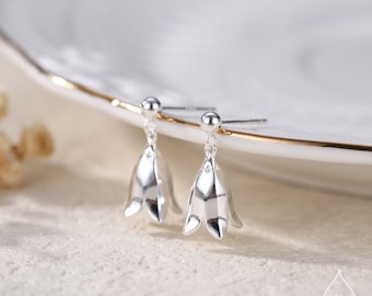 Può includere: Un paio di orecchini pendenti a forma di campana in argento. Gli orecchini sono delicati e presentano un design semplice.