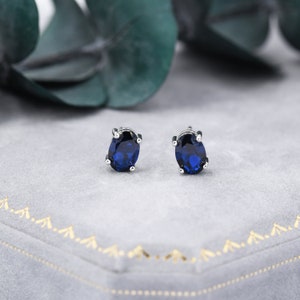 Op de afbeelding: Een paar zilveren oorbelletjes met ovale blauwe edelstenen.