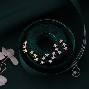 May include: Three sets of star-shaped earrings with clear cubic zirconia stones. The earrings are in gold, rose gold, and silver.