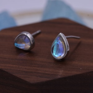 May include: A pair of silver teardrop earrings with iridescent rainbow moonstone stones.