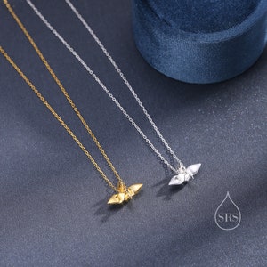 May include: Two delicate necklaces with origami bird pendants. One necklace has a gold pendant and the other has a silver pendant.