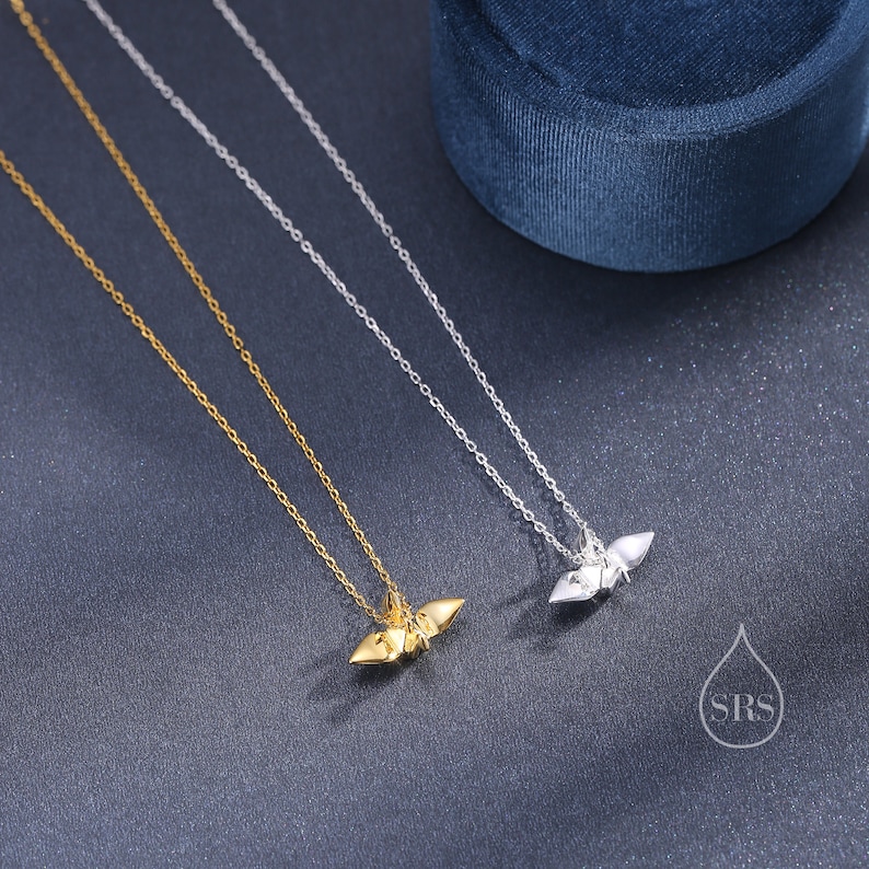 May include: Two delicate necklaces with origami bird pendants. One necklace has a gold pendant and the other has a silver pendant.