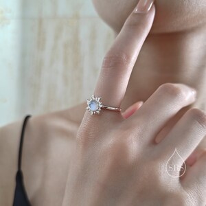 Puede incluir: Un anillo de plata con una piedra de luna engastada en un dise&ntilde;o de sol.
