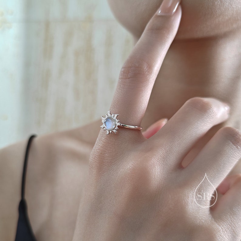 Puede incluir: Un anillo de plata con una piedra de luna engastada en un dise&ntilde;o de sol.