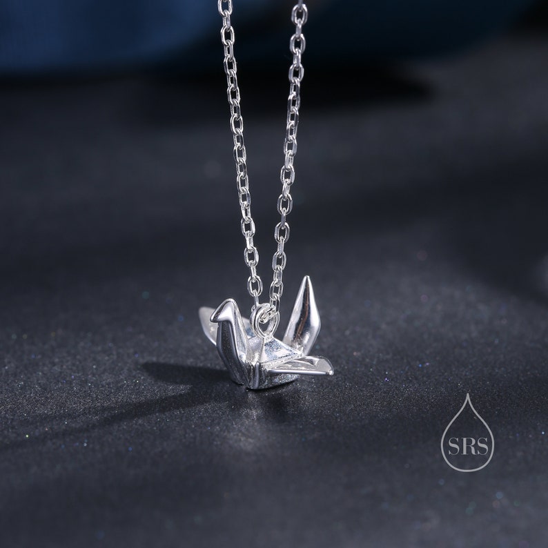 May include: A silver chain necklace with a silver origami crane pendant.