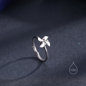 Puede incluir: Un anillo de plata con un delicado diseño de molino de viento. El anillo es simple y elegante, perfecto para el uso diario.