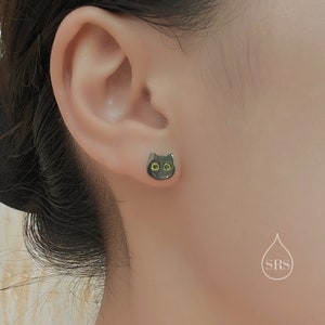 Peut inclure: Une paire de boucles d'oreilles clous en forme de chat noir avec des yeux jaunes. Les boucles d'oreilles sont port&eacute;es au lobe de l'oreille gauche.