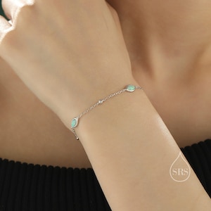 Puede incluir: Un brazalete de cadena de plata con tres piedras de ópalo verde de forma ovalada y un pequeño acento de piedra clara.