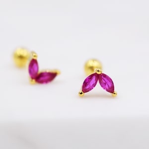 Peut inclure: Une paire de boucles d'oreilles pour le corps en or avec une pierre précieuse rose en forme de marquise sur chaque boucle d'oreille.