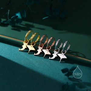 May include: Five hoop earrings with a small hammerhead shark charm hanging from each. The hoops are in different metal finishes: gold, rose gold, and silver.