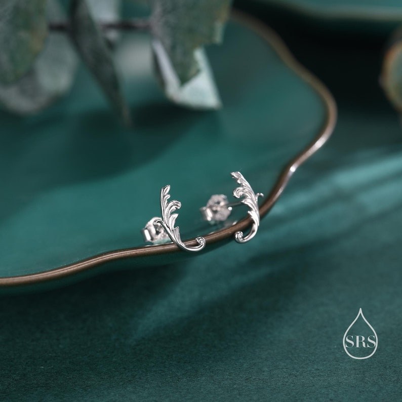 May include: A pair of silver leaf-shaped stud earrings. The earrings are delicate and have a simple design.