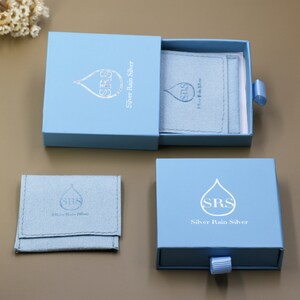 May include: A light blue jewelry box with a drawer. The box has a silver rain drop logo with the text "SRS Silver Rain Silver".