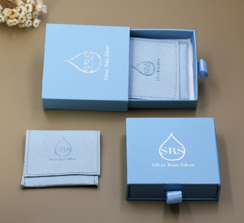 May include: A light blue jewelry box with a drawer. The box has a silver rain drop logo with the text "SRS Silver Rain Silver".