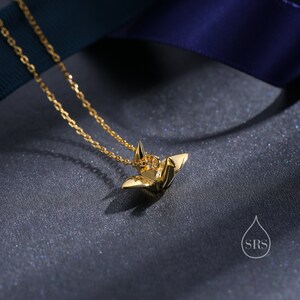 May include: A gold origami crane pendant necklace. The crane is a symbol of peace and good luck.
