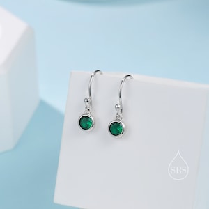 May include: A pair of silver dangle earrings with green gemstone accents.