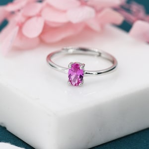 May include: A silver ring with a pink oval gemstone.
