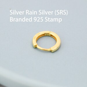 May include: A gold hoop earring with a 925 stamp. The earring is made of silver and is a simple, classic design.