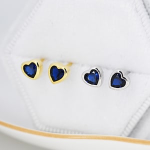 Könnte beinhalten: Ein Paar herzförmige Ohrringe mit blauen Edelsteinen. Die Ohrringe sind in Gold und Silber erhältlich.