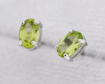 May include: A pair of silver stud earrings with oval-shaped green peridot gemstones.