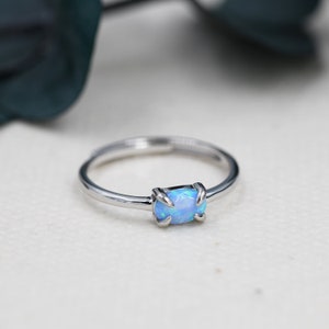 May include: A silver ring with a blue opal gemstone set in a claw setting.