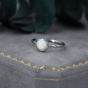 May include: A silver ring with a round, white opal gemstone.