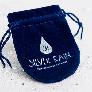 May include: A navy blue velvet jewelry pouch with a drawstring closure. The pouch features the text "SILVER RAIN STERLING SILVER JEWELLERY" in silver lettering, along with a silver raindrop logo.