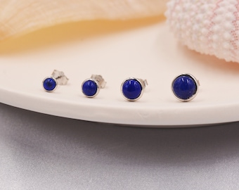 May include: Three pairs of silver stud earrings with blue lapis lazuli gemstones. The earrings are arranged in order of size, with the smallest on the left and the largest on the right.