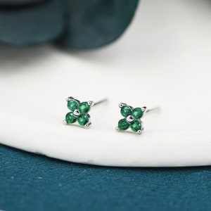 Peut inclure: Une paire de boucles d'oreilles clous en argent avec un motif de trèfle à quatre feuilles serti de pierres précieuses vertes.