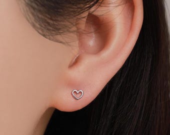 May include: A pair of silver heart-shaped stud earrings. The earrings are small and delicate, and they are perfect for everyday wear.