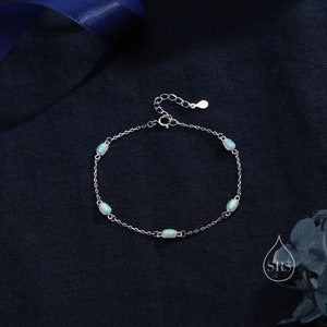 May include: A silver chain bracelet with four oval-shaped opal stones. The bracelet has a lobster clasp closure.