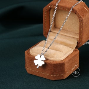 May include: A silver necklace with a four-leaf clover pendant in a brown velvet jewelry box.