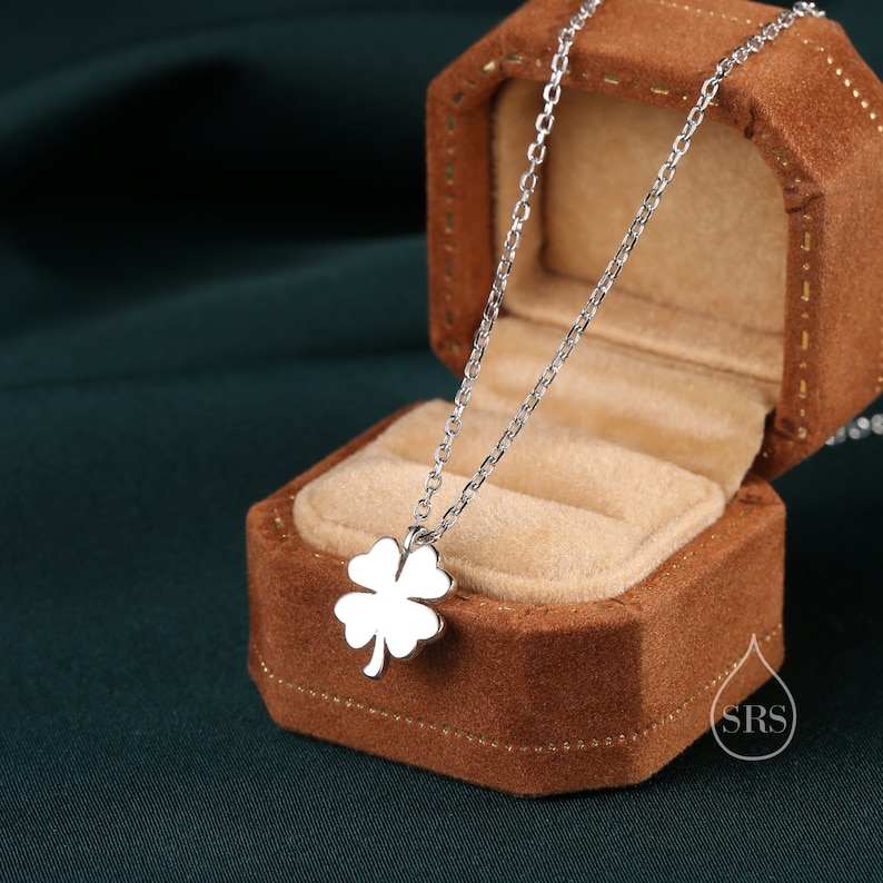 May include: A silver necklace with a four-leaf clover pendant in a brown velvet jewelry box.