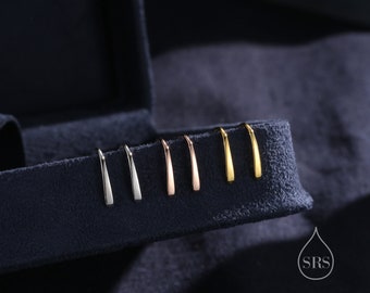 Könnte beinhalten: Ein Set mit sechs kleinen, dünnen, gebogenen Ohrringen in verschiedenen Metalloberflächen: Silber, Roségold und Gold. Die Ohrringe werden in einer samtenen Box präsentiert.
