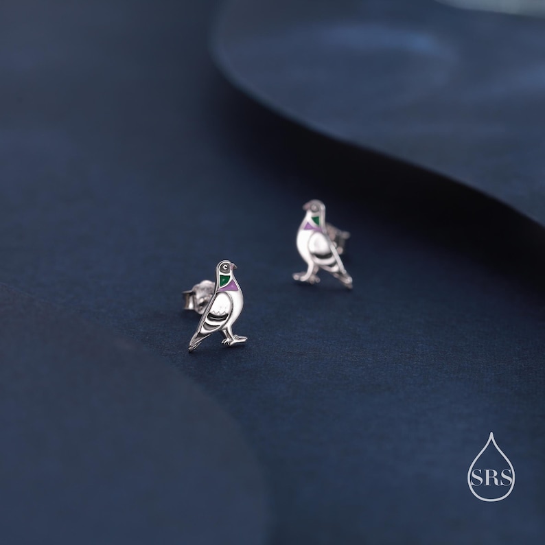 May include: A pair of silver dove earrings with green and purple enamel accents. The doves are facing to the right.