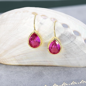 May include: A pair of gold teardrop earrings with pink gemstone accents.