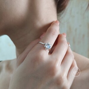 Puede incluir: Un anillo de plata con una piedra de luna engastada en un dise&ntilde;o de sol.