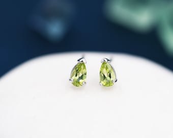May include: A pair of silver stud earrings with pear-shaped green peridot gemstones.