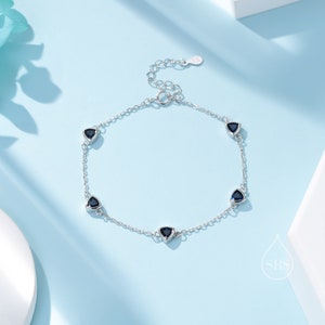 May include: A silver chain bracelet with five blue triangular gemstones. The bracelet has a lobster clasp closure.