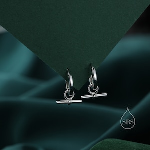 May include: A pair of silver hoop earrings with a small, horizontal bar hanging from each hoop.