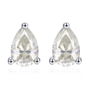 May include: A pair of pear-shaped stud earrings. Each earring features a clear, faceted gemstone set in a silver-colored metal. The earrings have a simple, elegant design, with a small silver ball at the top and two at the bottom.