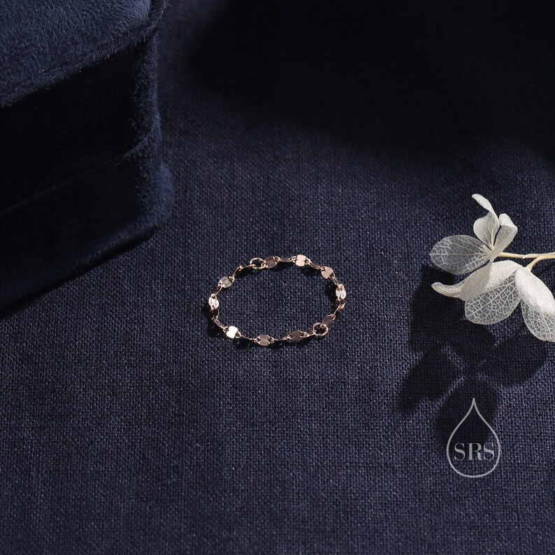 May include: A delicate gold chain bracelet with a linked design. The bracelet is on a dark blue fabric background.
